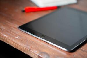 Tablet on Wooden Surface with Red Pen photo