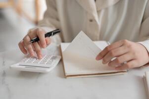 A close-up image of a woman using a calculator at a table, checking and calculating her budget. photo