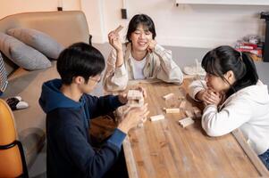 A group of joyful young Asian friends is playing a table game together at home. photo