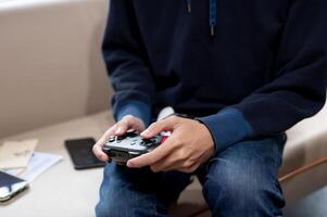 A close-up image of a man is holding a joystick and playing a game in the living room. photo