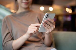 A cropped image of a woman using her smartphone while sitting at a sofa in a hotel lounge or a cafe. photo