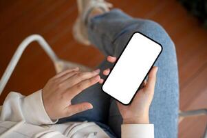 Top view image of a woman in casual clothes is using her smartphone while relaxing indoors. photo