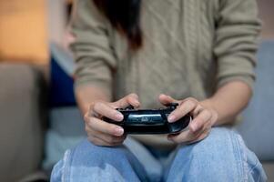 A close-up image of a woman is holding a joystick and playing a game on the sofa at home. photo