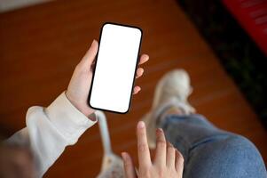 Top view image of a woman in casual clothes is using her smartphone while relaxing indoors. photo
