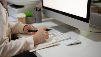 A woman is working on her tasks at her desk in the office, sitting in front of a computer. photo