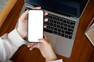 Top view image, A woman using her smartphone at a desk. A white-screen smartphone mockup. photo