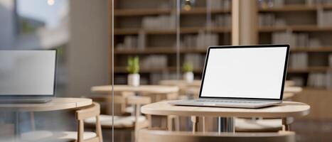 A close-up image of a laptop computer on a wooden table near the window in a coffee shop. photo