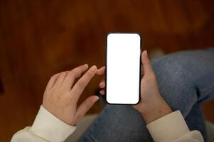 Top view image of a woman in jeans is using her smartphone while sitting indoors. photo