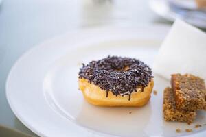 Chocolate-sprinkled donut on a white plate photo
