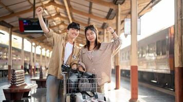 Cute couple are walking down the platform with a cart, commuting by a train at a railway station. photo