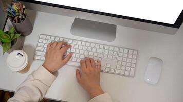 Top view of a woman is working on her computer at a desk, typing on keyboard, responding to emails. photo