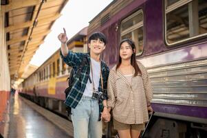 Asian couple travelers are commuting by train together, walking on a platform at a railway station. photo