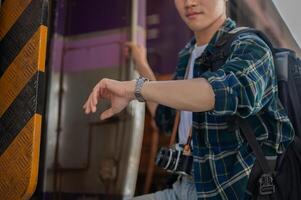 A handsome Asian man traveler is checking time on his wristwatch while getting off the train. photo