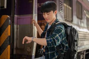 A handsome Asian man traveler is checking time on his wristwatch while getting off the train. photo