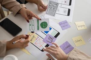 A meeting table with a graphic designer team and various prototype for a new mobile application. photo
