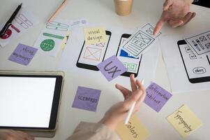 A meeting table with a graphic designer team and various prototype for a new mobile application. photo