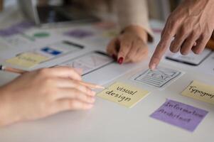 Close-up image of creative UX UI graphic designer team pointing their finger at a sticky note. photo