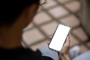 Close-up image of a man using his smartphone while sitting outdoors. People and technology concepts photo