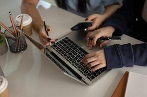 Cropped image of two female friends are working on a project together at a table indoors. photo
