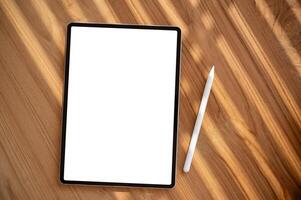 A wooden desk workspace with a white-screen digital tablet mockup and a tablet pen. photo