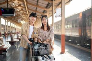 Cute couple are walking down the platform with a cart, commuting by a train at a railway station. photo
