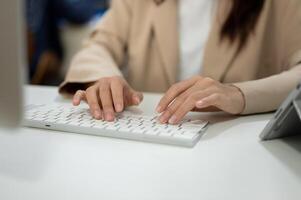Close-up image of a businesswoman working at her desk in the office, typing on keyboard computer. photo