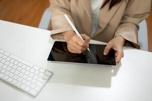Close-up image of a businesswoman using her digital tablet at her office desk. photo