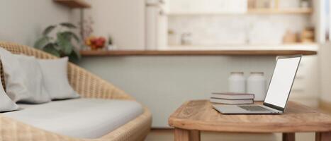 A laptop on a hardwood coffee table in a cosy Scandinavian living room with a cosy wicker couch. photo
