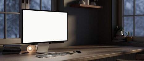 A computer desk in a modern room at night, a white-screen computer mockup on a hardwood desk. photo
