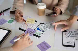 A meeting table with a graphic designer team and various prototype for a new mobile application. photo