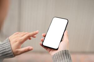 A close-up image of a white-screen smartphone mockup in a woman's hand with a blurred background. photo