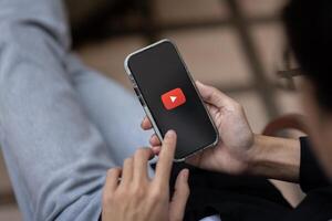 A man using Youtube application on his iPhone while sitting outdoors. close-up image photo