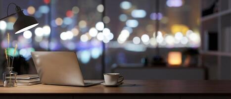 Back view of an office desk with a laptop, a table lamp, and accessories in a dark room at night photo