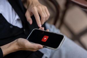 A man using Youtube application on his iPhone while sitting outdoors. close-up image photo