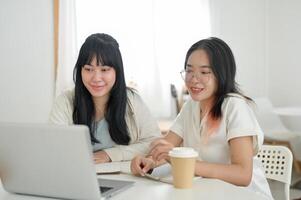 Two students are meeting at a cafe to work on a co-project or study together, looking at a laptop. photo