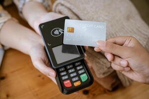 A close-up image of a customer tapping her credit card with a payment terminal in a clothing store. photo