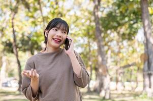 A woman enjoys talking on the phone with her friend while strolling around in the park. photo