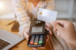 A close-up image of a customer tapping her credit card with a payment terminal in a clothing store. photo