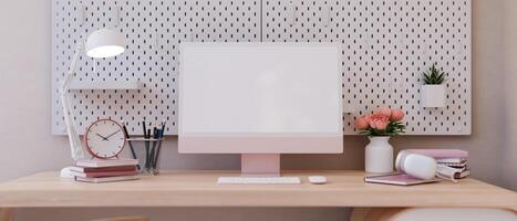 Front view image of a female office desk in pink with a pink computer mockup and accessories. photo