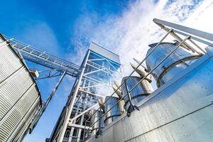 View from below on steel grain elevators. Industrial agriculture elevators with harvested grain. Modern up to date factory. Selective focus. photo