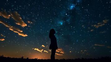 Silhouette of a girl looks at the starry sky. . photo