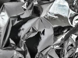 Thin sheet of silver leaf background with shiny crumpled uneven surface photo