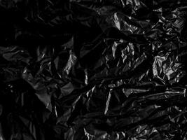 Transparent plastic wrap on the black background. Clean blank texture overlay effect template. Isolated wrinkle surface branding mock-up. photo