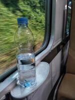 Close up view of mineral water bottle standing near train window. Stay fresh during the trip. photo