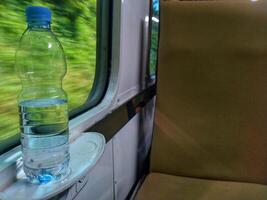 Close up view of mineral water bottle standing near train window. Stay fresh during the trip. photo