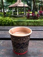 Paper Cup of Coffee on Bench in Outdoor Setting, Warm Beverage in Disposable Cup on Vintage Bench, Rustic Coffee Moment using Paper Cup on Outdoor Bench With copy space for text quotes photo