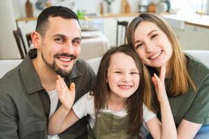 Happy family at home. Mother father children daughter relaxing on sofa indoor. Mom dad parents kid girl relax playing hugging having fun together. Family smiling laughing enjoying tender moment photo