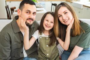 Happy family at home. Mother father children daughter relaxing on sofa indoor. Mom dad parents kid girl relax playing hugging having fun together. Family smiling laughing enjoying tender moment photo