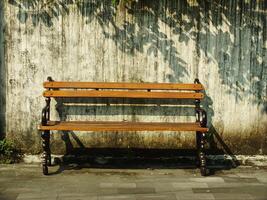 Old wooden bench in front of old dirty white wall. Retro vintage concept background image. Oldies but goodies photo