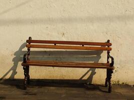 Old wooden bench in front of old dirty white wall. Retro vintage concept background image. Oldies but goodies photo